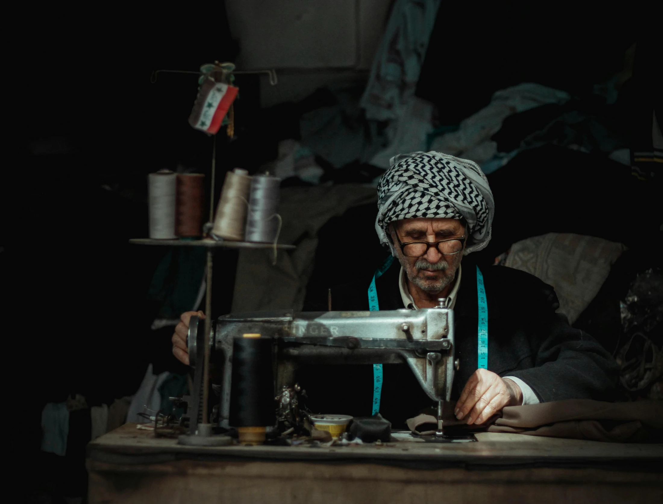 a man in a white turban is sitting behind a sewing machine