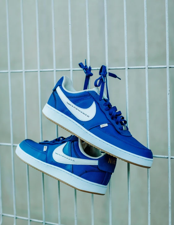 a pair of blue tennis shoes hang from a metal rack