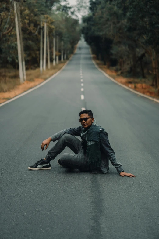 a man sitting on the middle of a street, with his hands on his knees