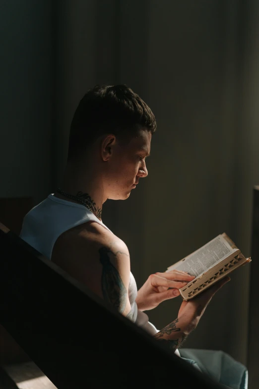 a young man sitting down reading a book