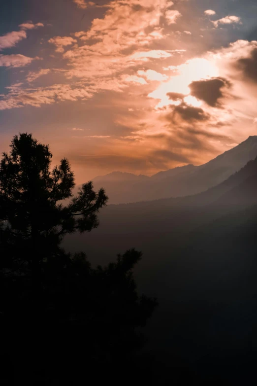 the sun sets behind some mountains in the distance