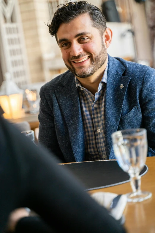 a man sitting at a table smiling for a po