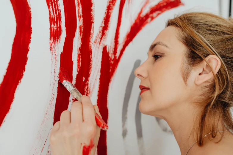 a woman painting a large american flag with red paint