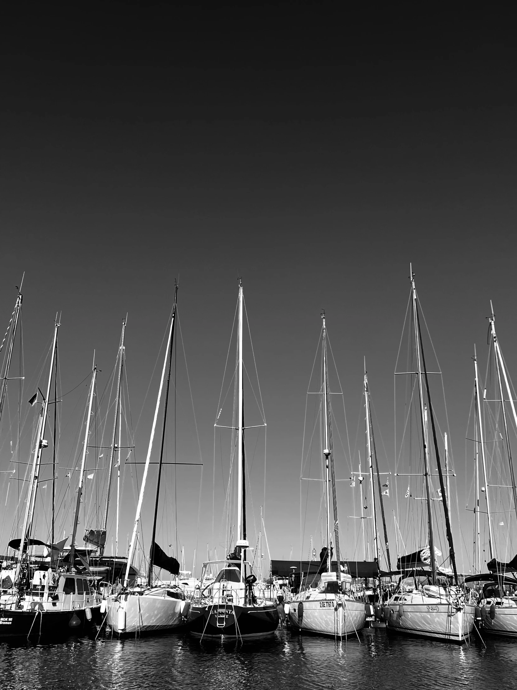 a black and white po of many sailboats docked