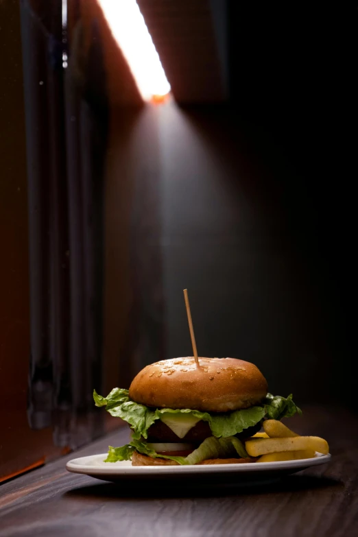 the plate has a burger and a glass on the table