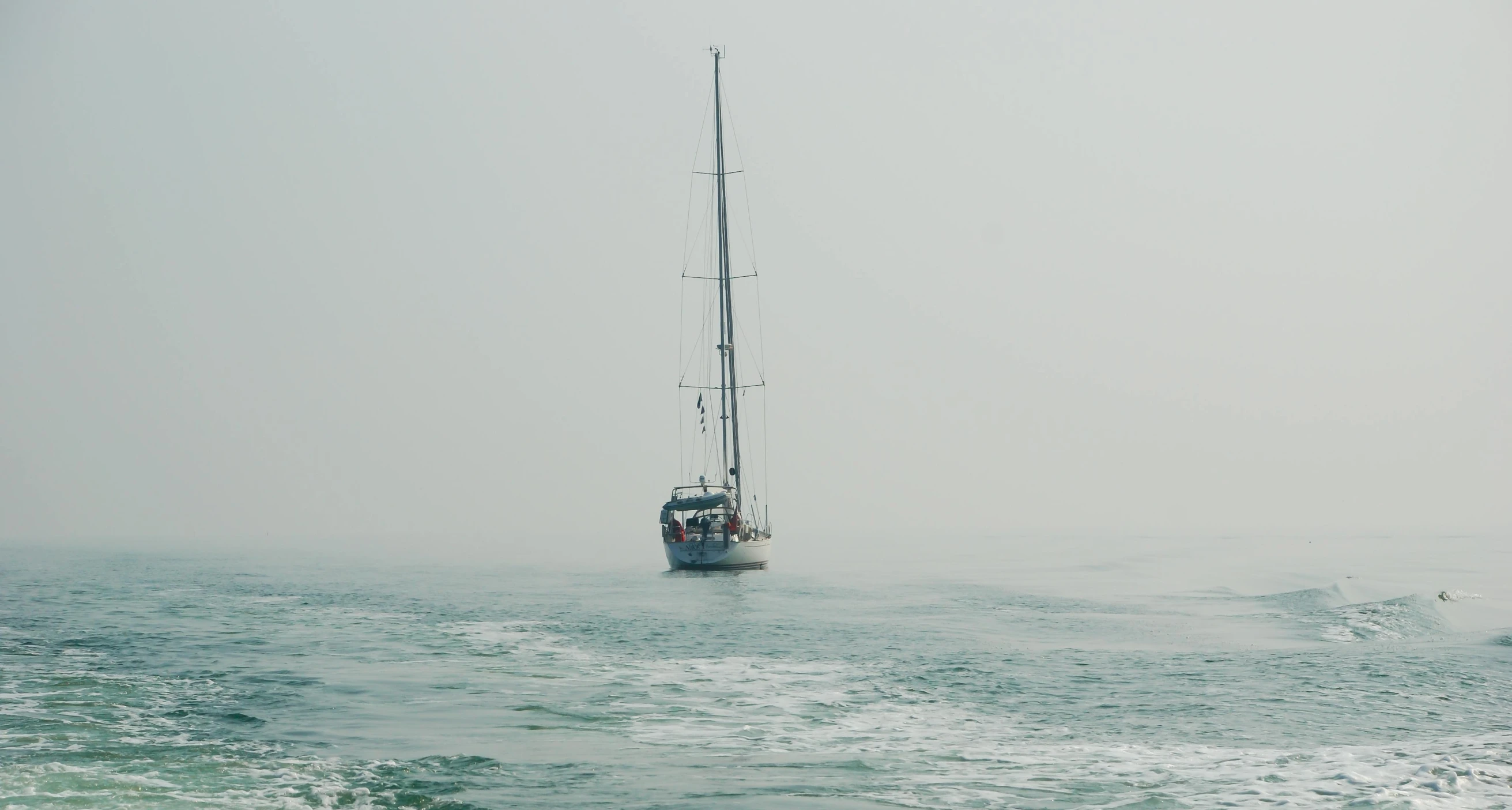 a boat floating in the ocean on a foggy day