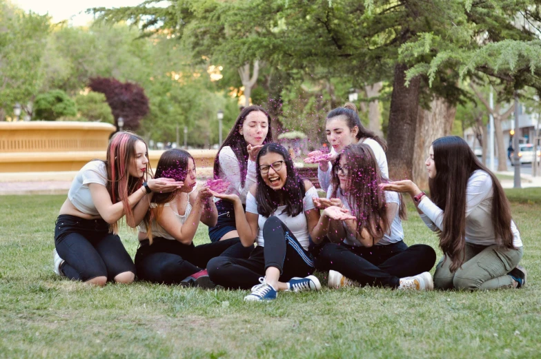 eight girls sit on the grass and have water