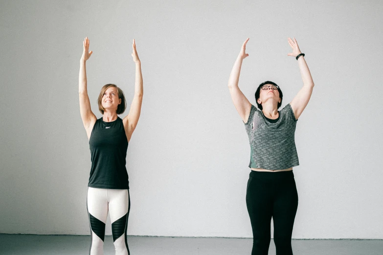two women with arms raised in a yoga position