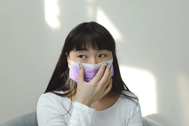 the young woman in a protective mask is covering her face