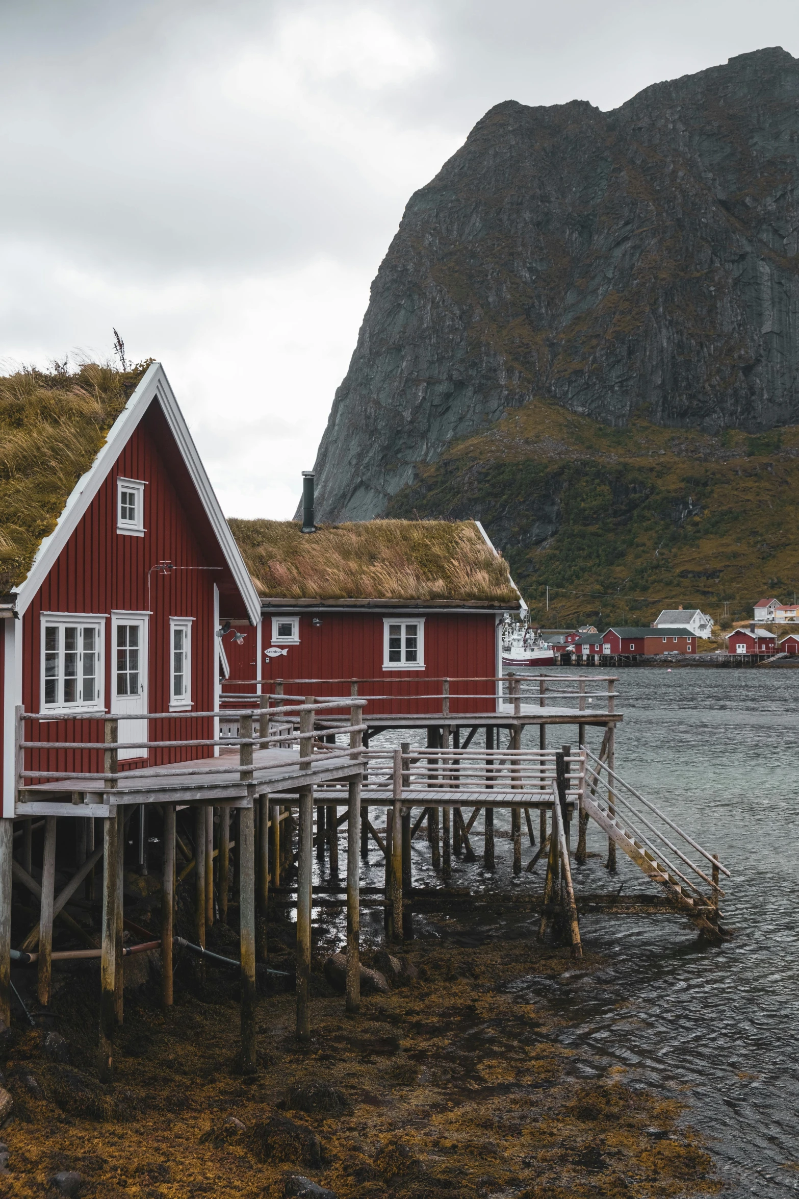 a red cabin on the water with a green roof