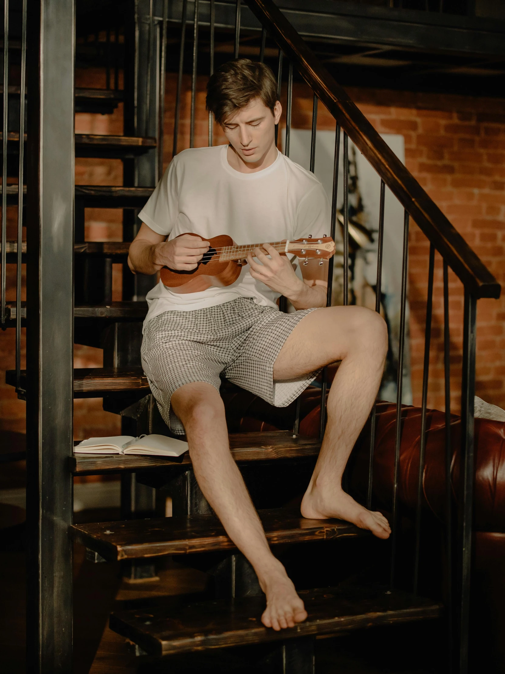 a young man sitting on stairs with a guitar