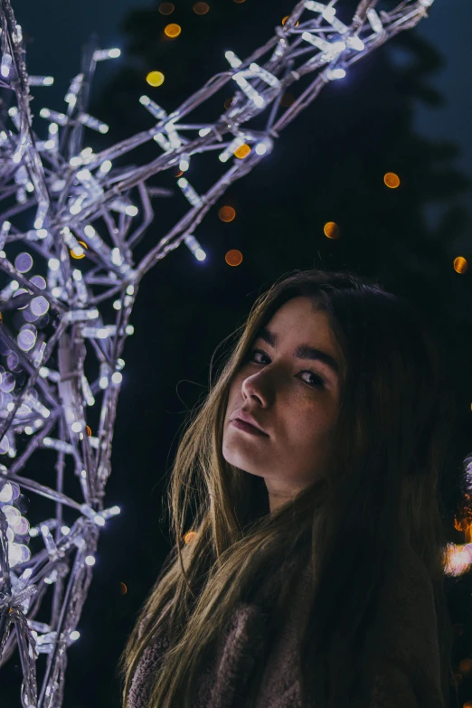 a woman looking at the camera, with lights behind her