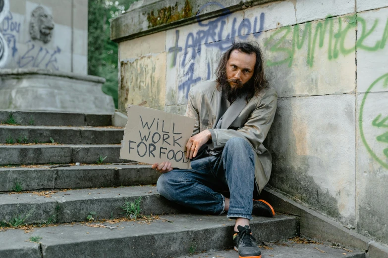 a man sitting on the steps holding a sign