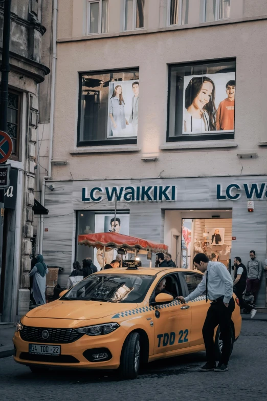 a yellow taxi cab and its driver are stopped on the street