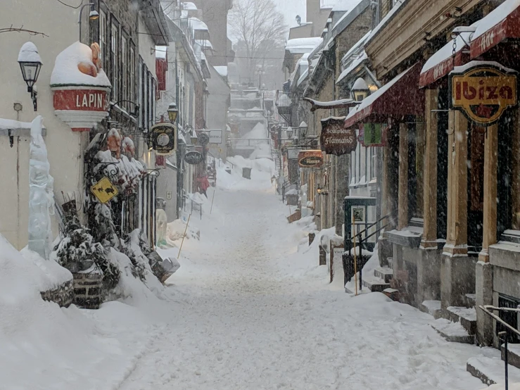 a narrow street covered in snow with buildings