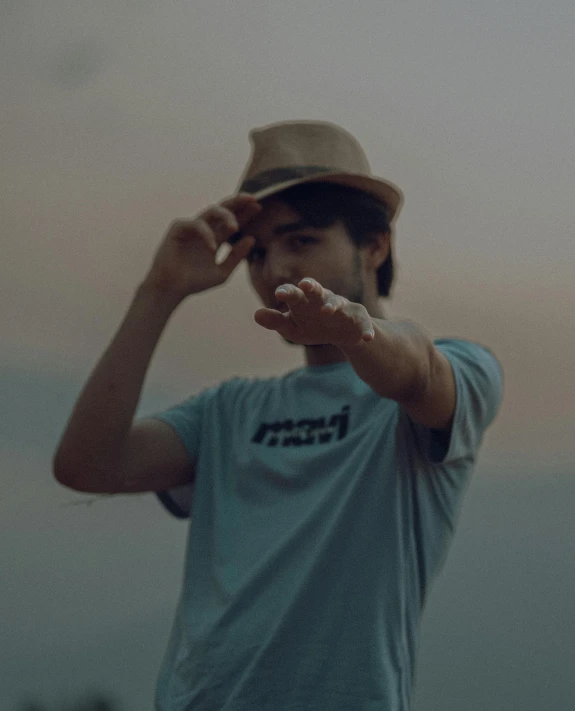 an adult holding his hat in the air while walking on a cliff