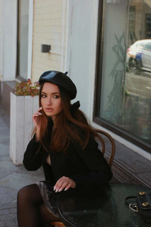 a woman sitting at a table wearing a black hat