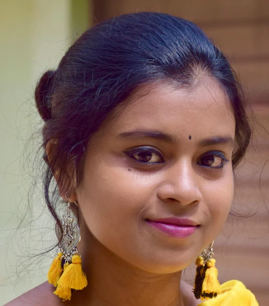 a young woman smiles while wearing yellow earrings