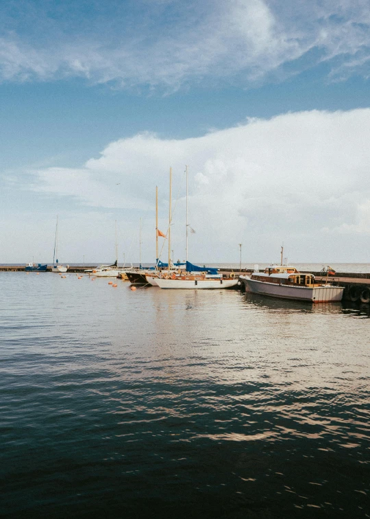 a harbor with boats sitting on the water and a cloudy blue sky