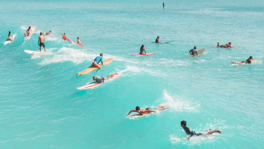 surfers paddle in the ocean while others on their surf boards rest