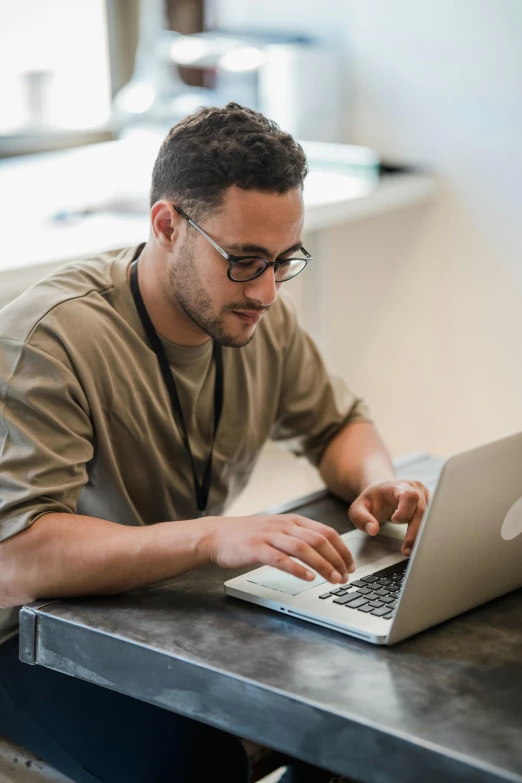 a man using a laptop computer sitting on top of a metal table