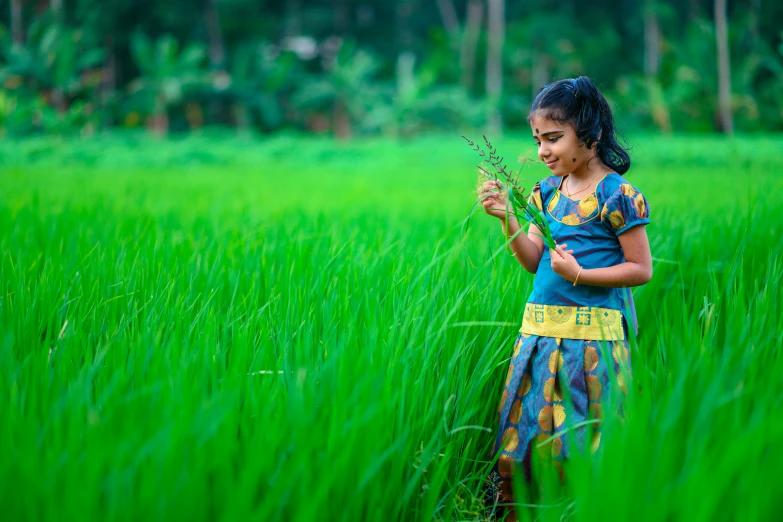 an indian girl in the green grass eating from a nch