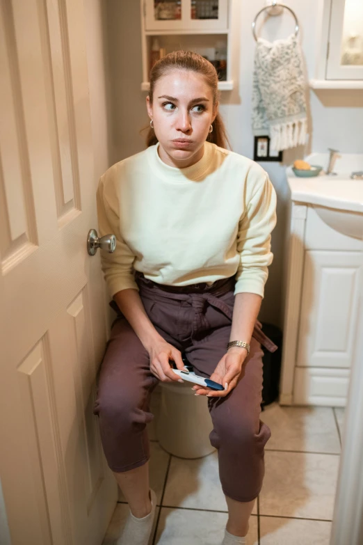 a woman is sitting on the toilet holding a phone