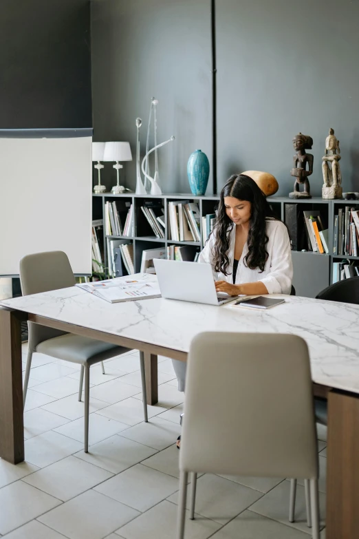 a woman sitting at a table with a laptop computer