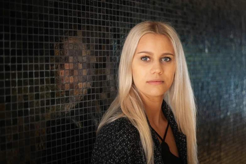 a woman is standing near the tiled wall