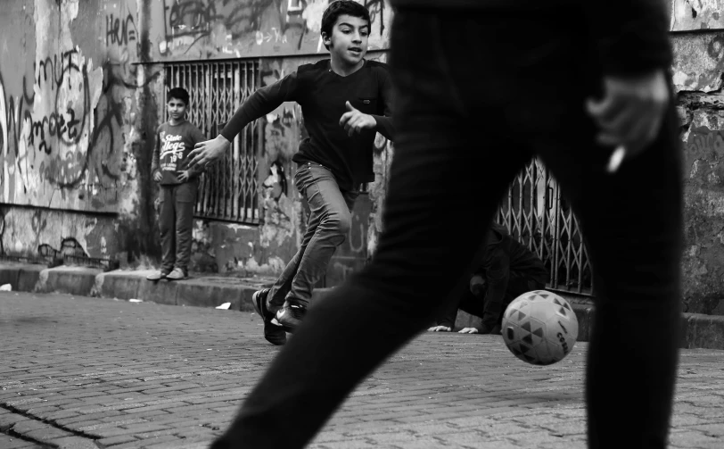 two boys playing soccer in the middle of a sidewalk