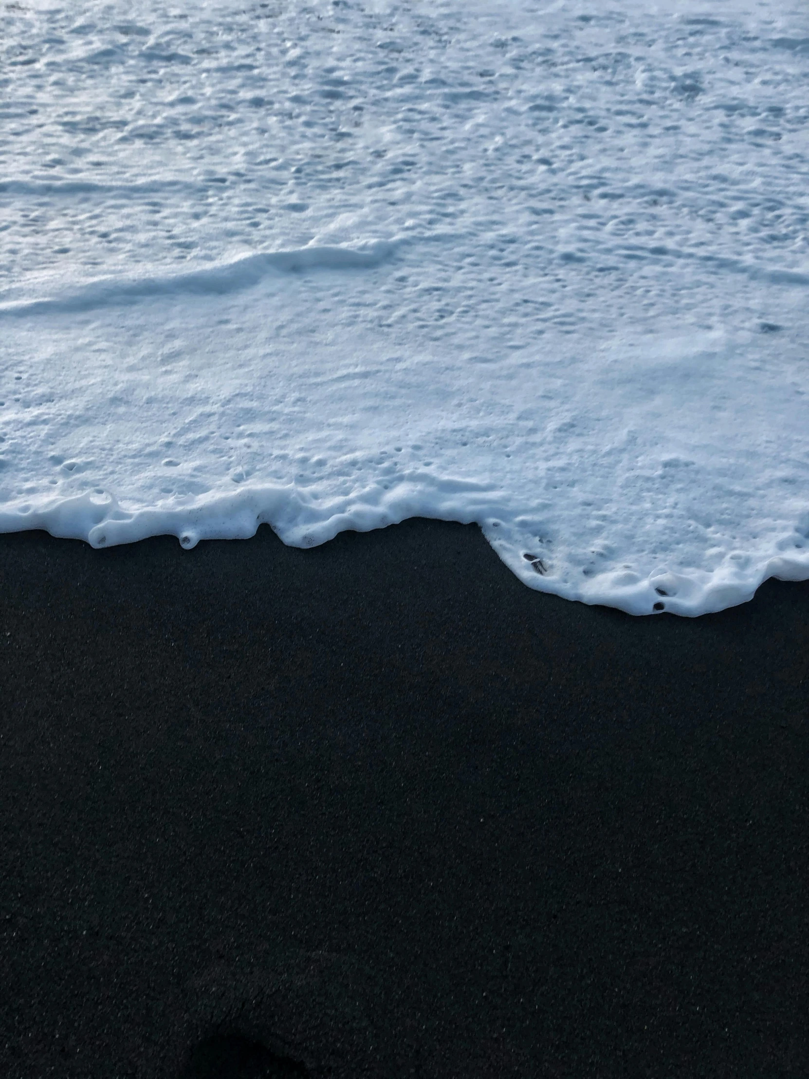 black sand and surf with the tide coming in