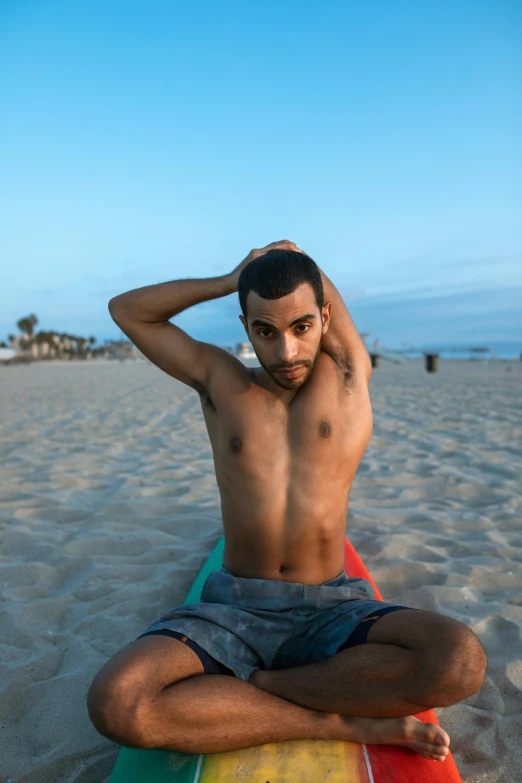 the man is sitting on his surfboard at the beach