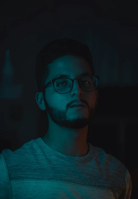 man with glasses staring in front of a green light