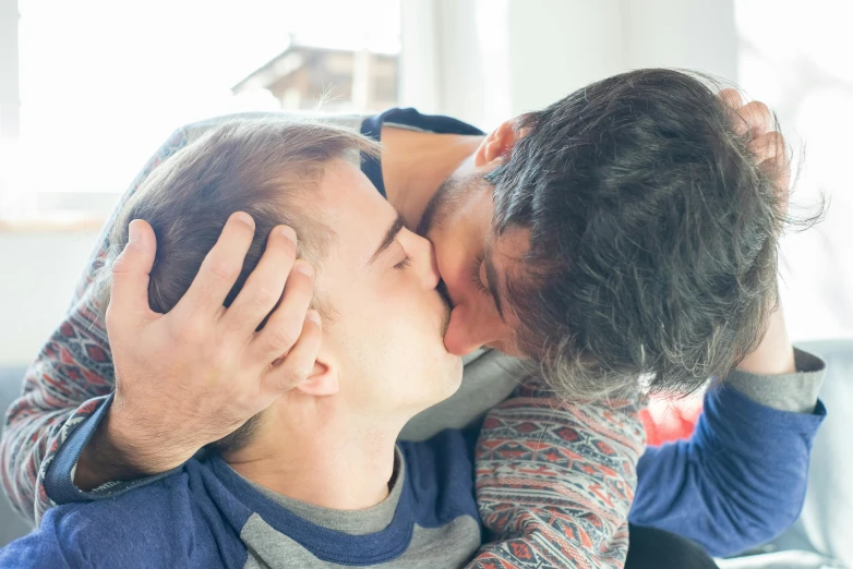 two people giving each other kisses on a couch