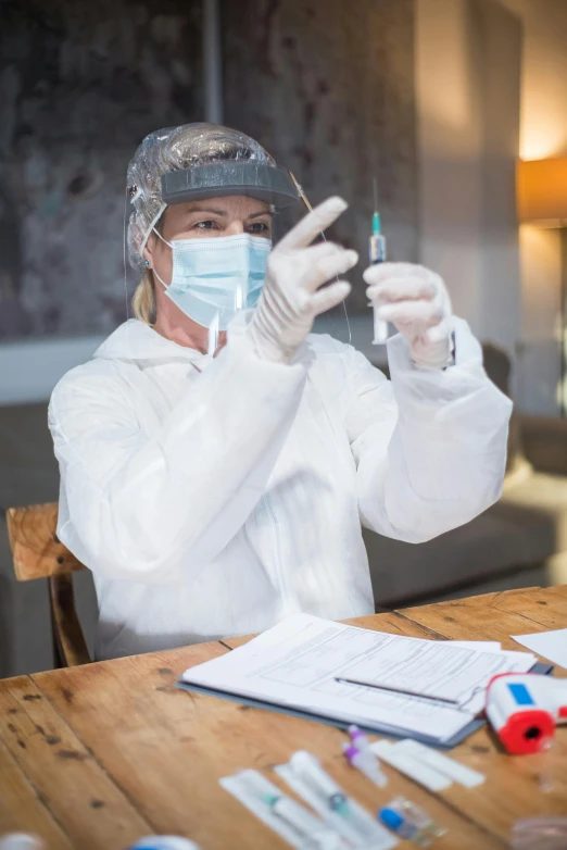 a woman in protective clothing holds up a toothbrush