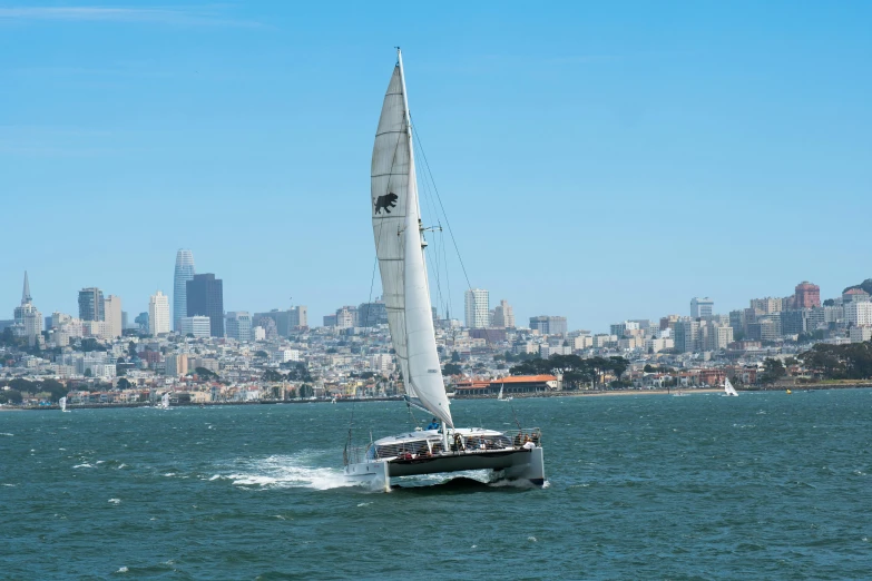 a sailboat is riding through the water in front of some tall buildings