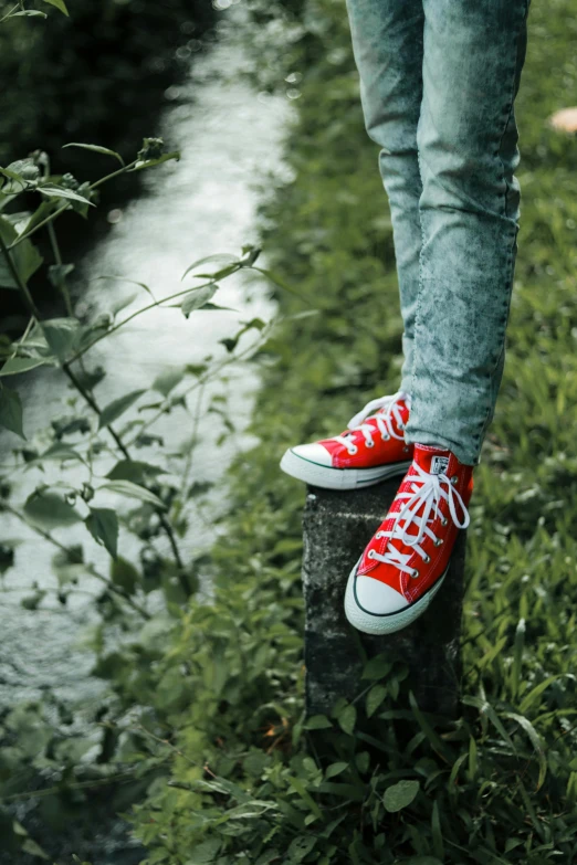 a person with tennis shoes stands on a concrete block outside