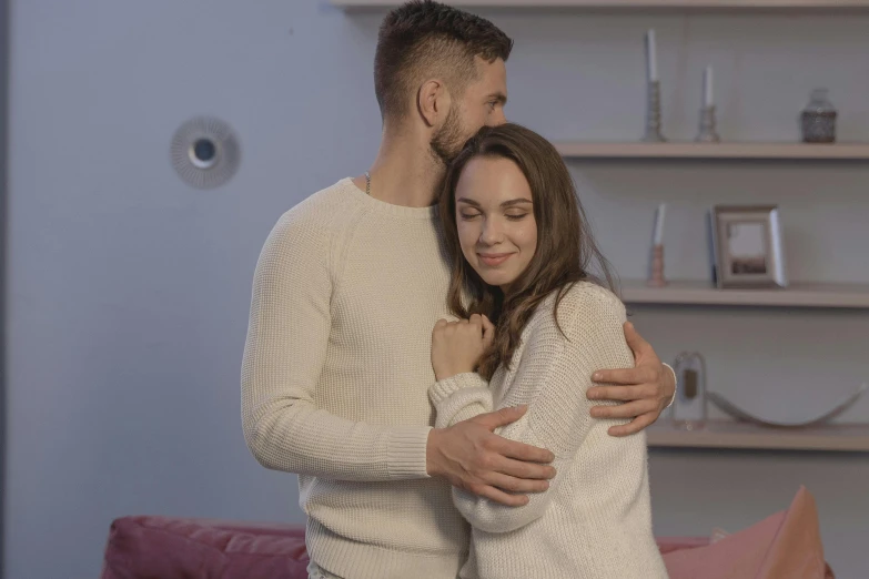 two people hugging and laughing in front of a bookshelf