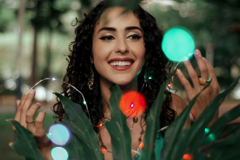 a girl smiling in a park surrounded by leaves and glowing lights