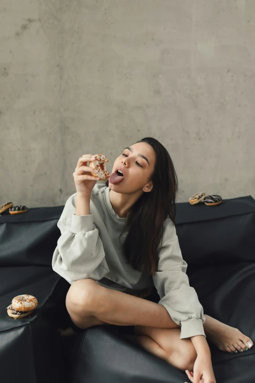 a woman is eating food on a black couch