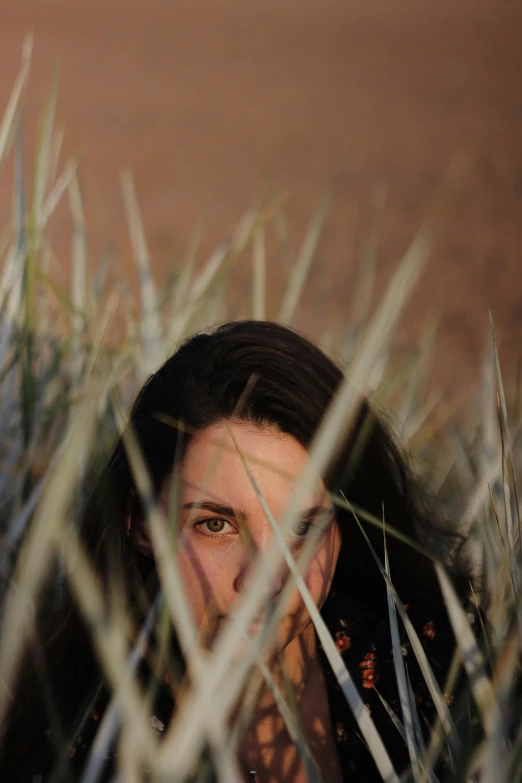 a woman's face is obscured by a background of long grass