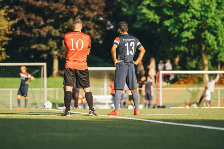 two young men are watching another man on a field