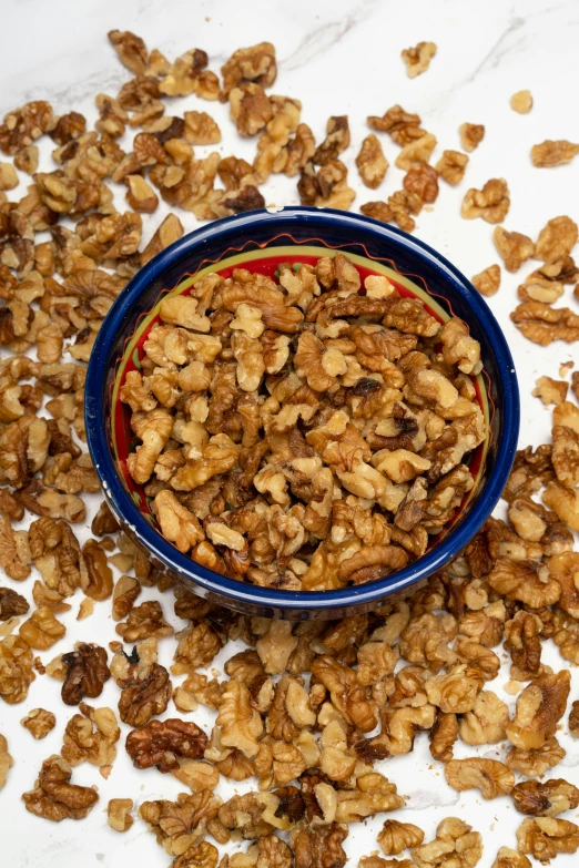 granola on a marble table with a blue bowl of nuts