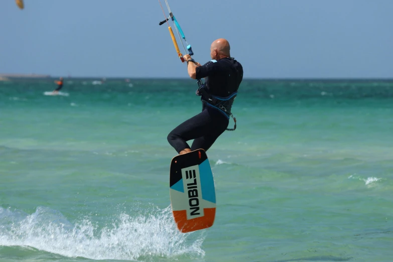 a man in a wet suit windsurfs across the water