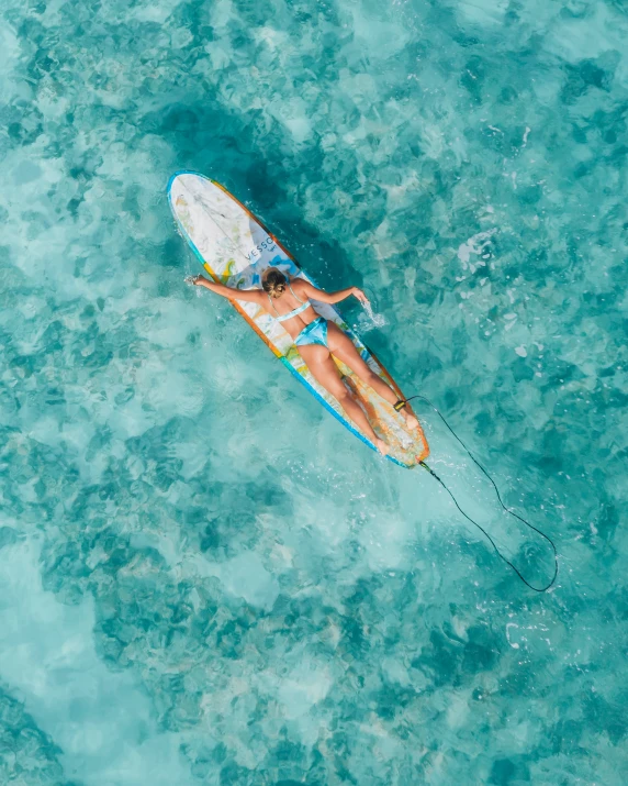 the girl on her surf board is laying down