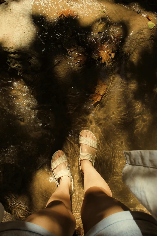 feet in sandals stand in water in the shade