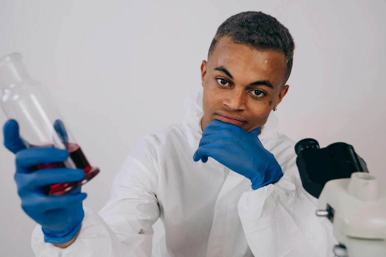 a man in blue gloves holds a beakle and a tube