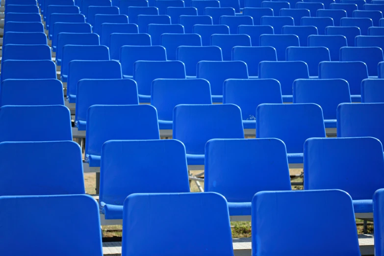 rows of blue chairs sitting in a stadium