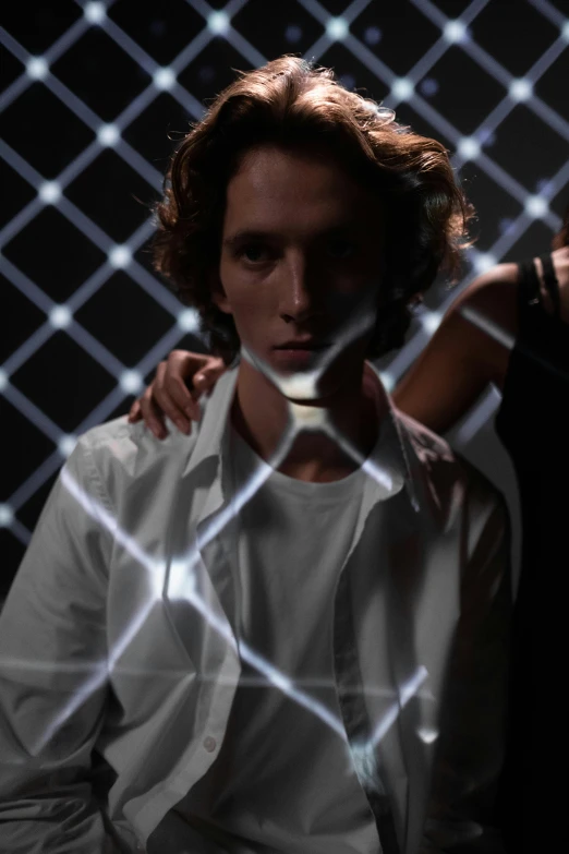 two young men leaning on each other with a chain link fence