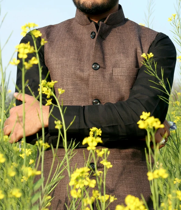 man wearing a jacket standing in flowers with his hands crossed